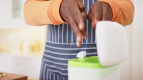 sección media de afroamericano hombre mayor compostaje de verduras residuos en la cocina, cámara lenta