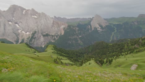 Handheld-pan-from-amazing-mountain-views-down-to-the-hill-bank-of-green-grass-meadow