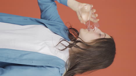 Vertical-video-of-The-young-woman-is-drinking-water.