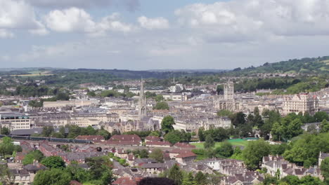 Toma-Aérea-Alejándose-De-La-Ciudad-De-Bath,-Incluida-La-Abadía-De-Bath---Tren-Gwr,-En-El-Suroeste-De-Inglaterra-En-Un-Día-Soleado-De-Verano-Con-Una-Cosecha-Estrecha