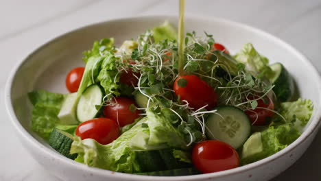 pouring dressing over a fresh green salad