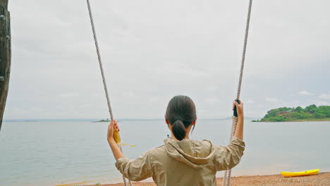 Close-up-girl-enjoys-flight-on-swing-on-summer-evening-near-sea-beach