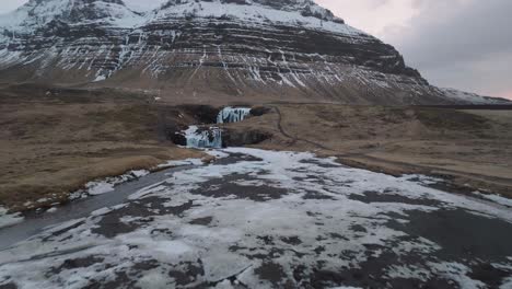 drone shot, cascadas bajo colinas volcánicas en el frío paisaje invernal de islandia
