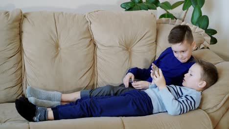 preschool boys holds modern mobile phone and plays cheerfully video game. focus on smartphone.