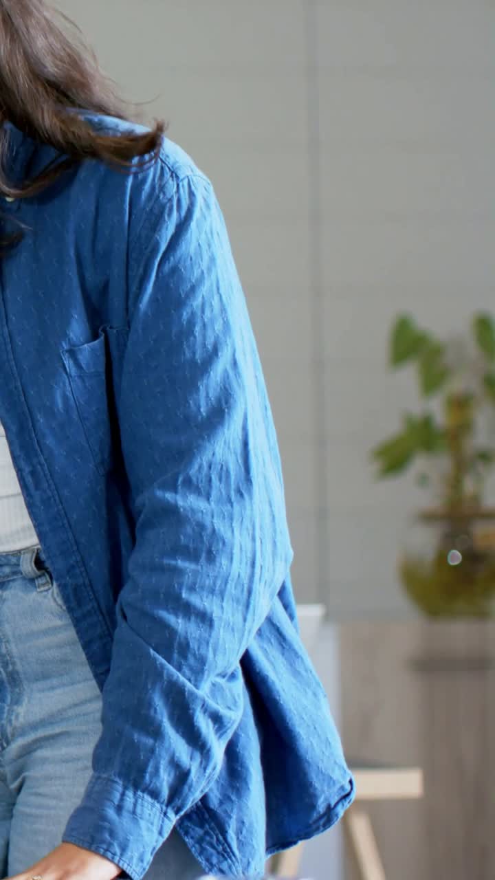 Donna seduta che usa uno stilo per toccare un tablet; un collega reagisce al tocco, posizionando un bicchiere e indicando una tecnologia da recensire.