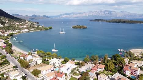 Nidri-Bay,-Boats-and-Small-Madouri-Island-at-Lefkada,-Greece---Aerial-Forward