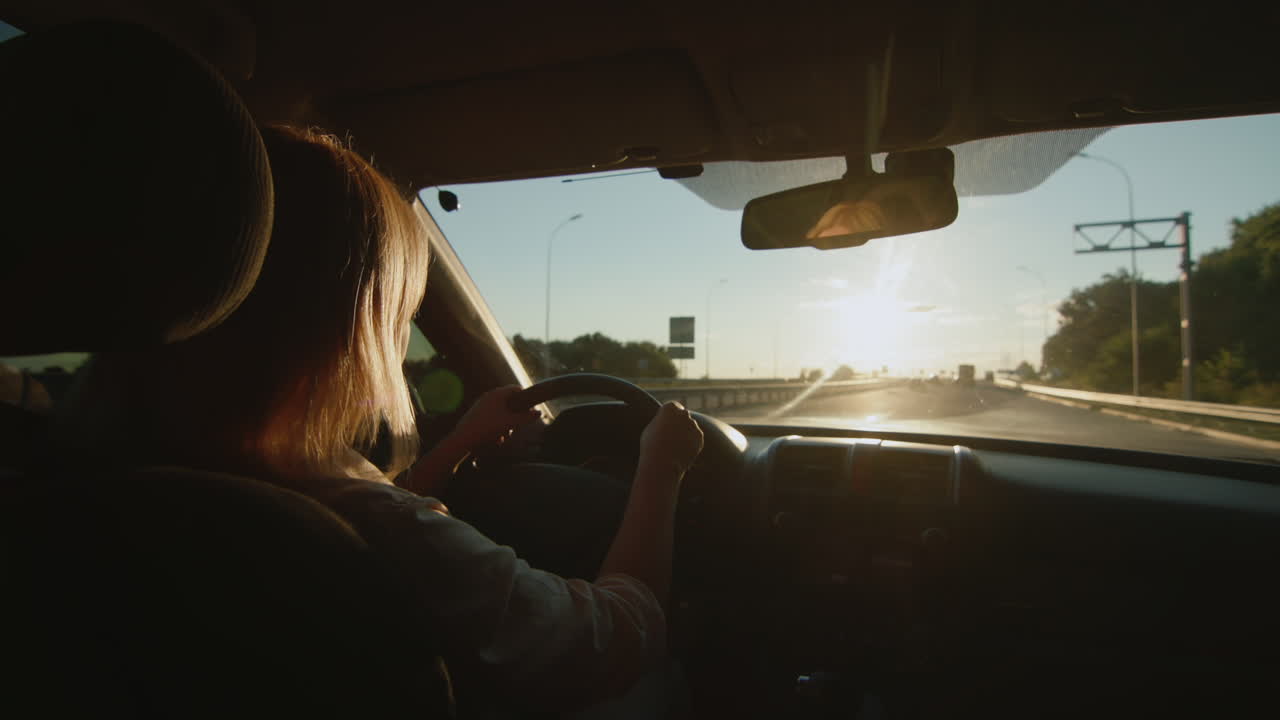 conductora de mediana edad conduce un automóvil al ponerse el sol 3