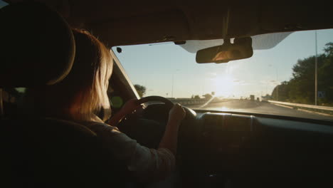 conductora de mediana edad conduce un automóvil al ponerse el sol 3