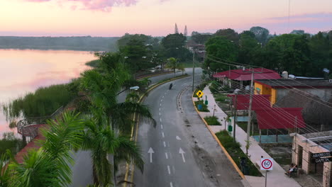 aerial of motorcycle driving on empty road in town of coba in quintana roo mexico at sunset golden hour