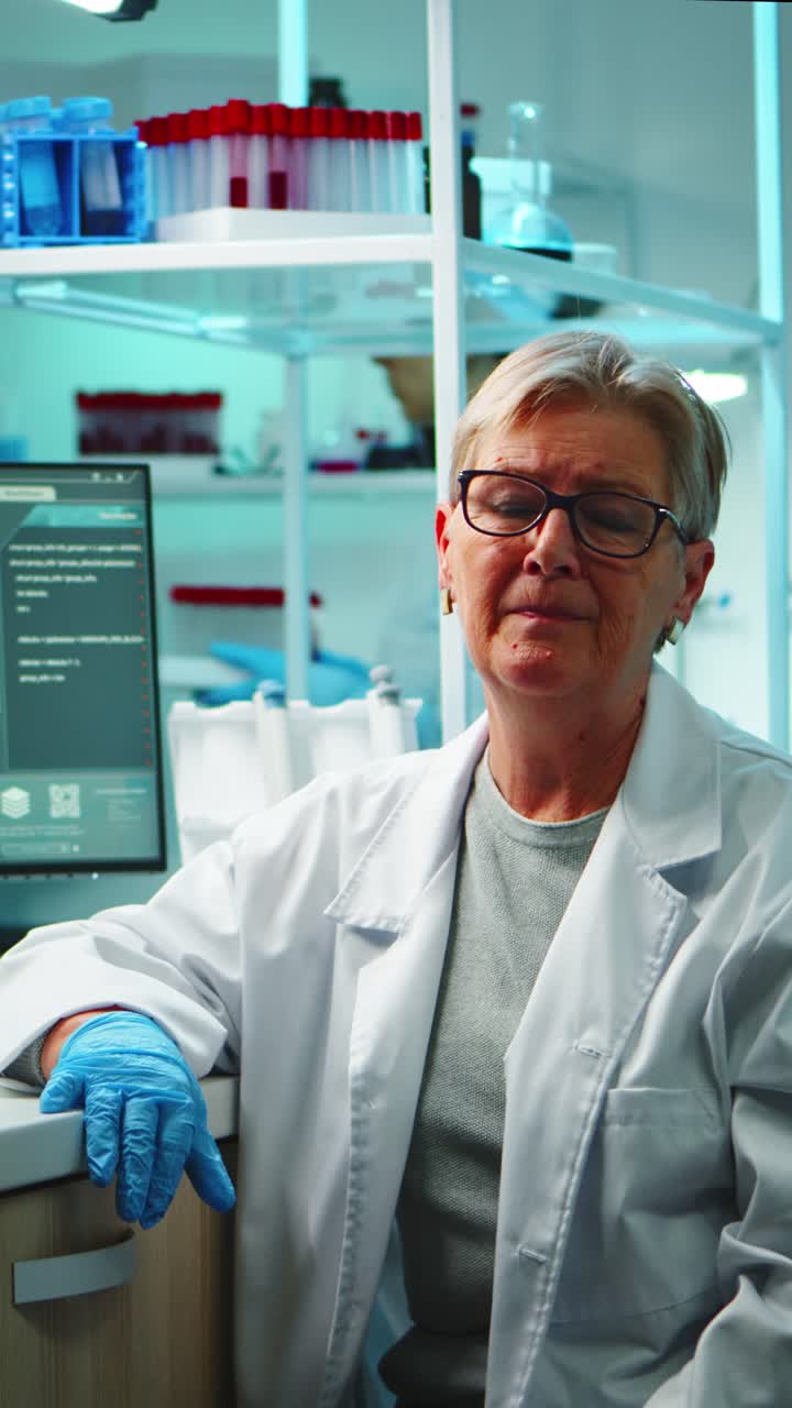 Vertical video: Portrait of old chemist woman with fatigued face in front of camera