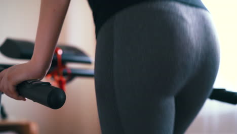 slim woman presses keys to start modern treadmill in room