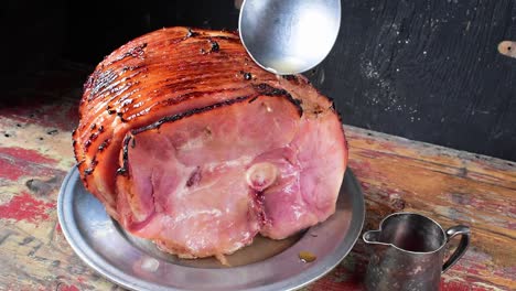 cucharón de jugo sobre jamón cortado en espiral al horno