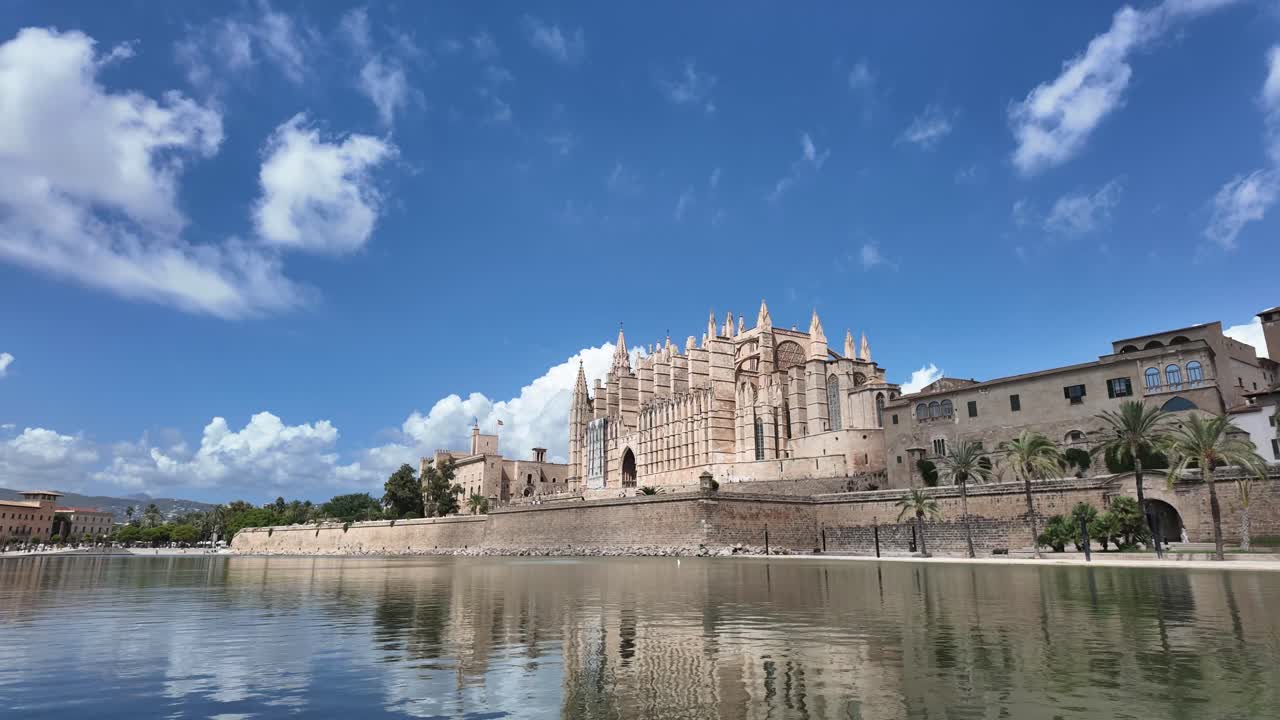 Timelapse of Palma de Mallorca historical city center and the cathedral reflected on the water, under a blue sky with some clouds