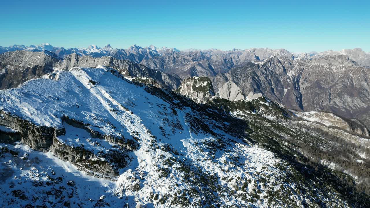 Filmato aereo con drone sopra Monte Raut, Italia: limpida giornata di dicembre con creste illuminate dal sole e pendii innevati in ombra. Ideale per filmato video in stock naturalistico invernale, alpino e cinematografico.