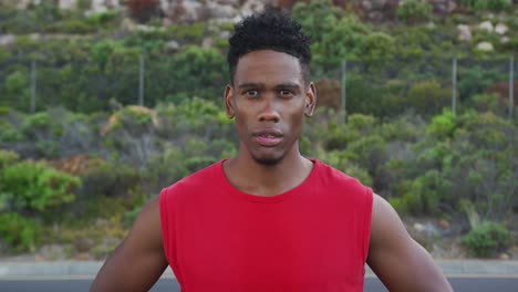 Portrait-of-african-american-man-exercising-outdoors-looking-at-camera-on-a-coastal-road