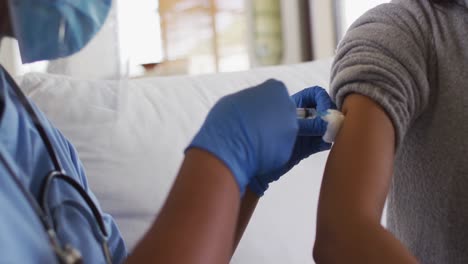 african american female doctor wearing face mask vaccinating african american patient