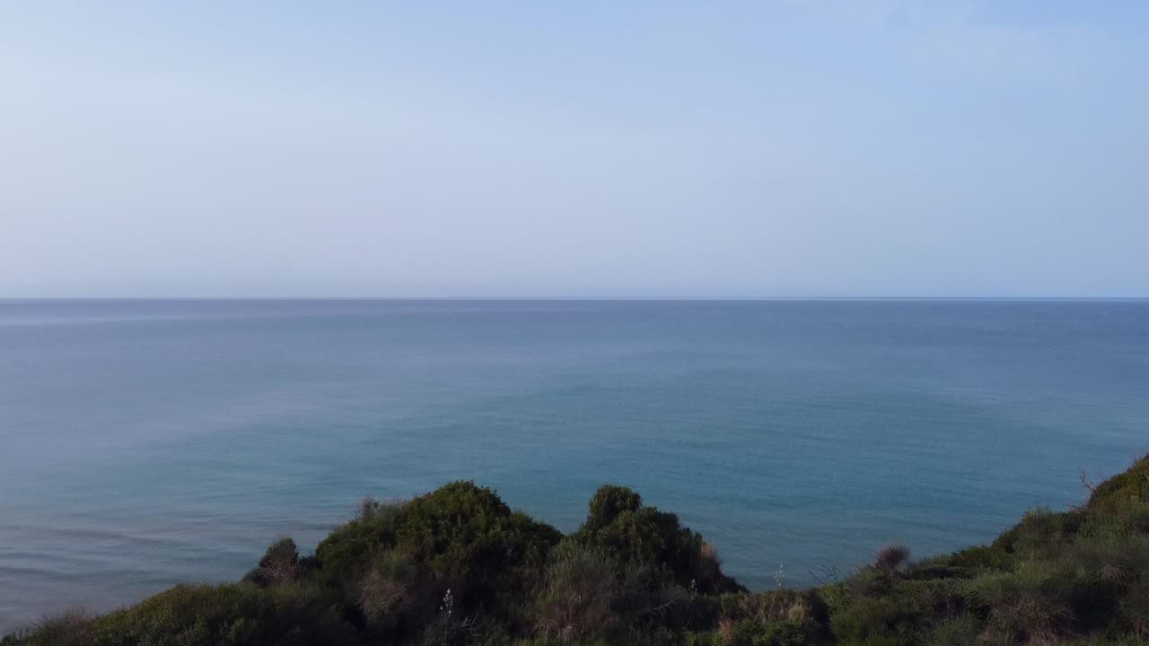 Volo aereo fluido in avanti sopra il bordo di una scogliera, riprese con drone nella paradisiaca natura selvaggia, canyon e spiaggia da sogno di Marathias, Corfù, Grecia.