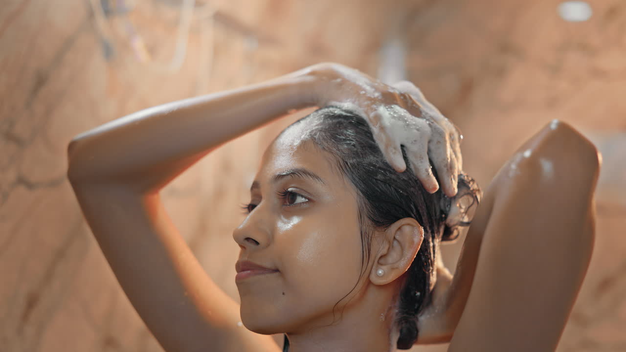 Donna rilassata che si lava i capelli con la schiuma dello shampoo durante la routine di cura mattutina.