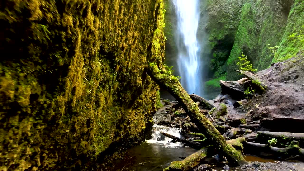 dolly fuera de la cascada oculta mili mili cayendo en una piscina natural rodeada de una densa vegetación verde, coñaripe, chile