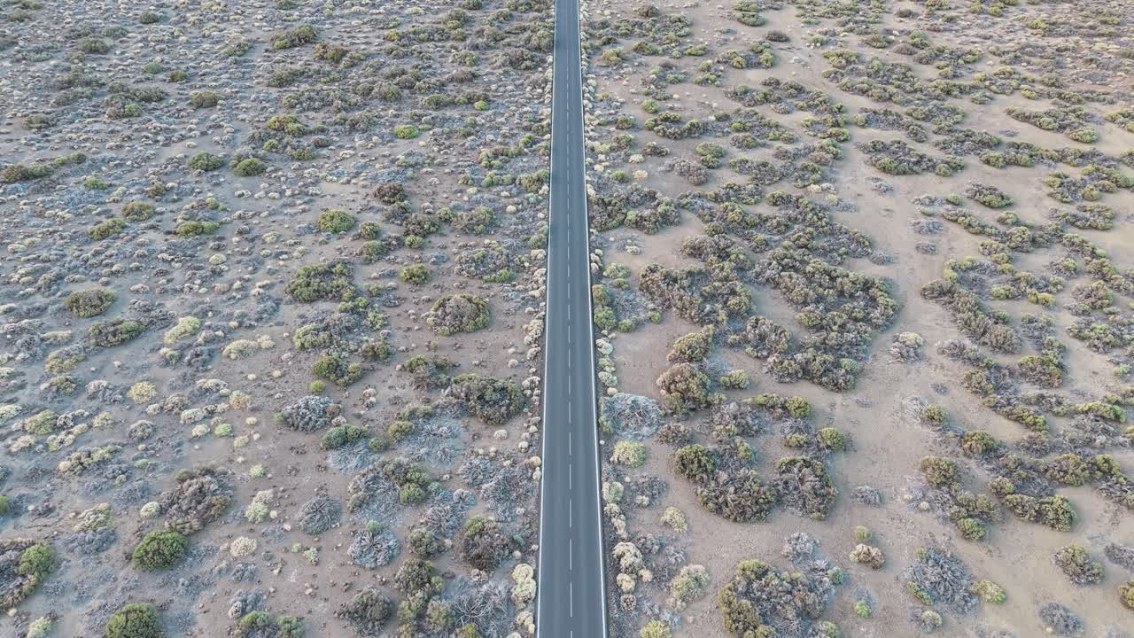 Aerial view over a barren landscape in Tenerife with a solitary road cutting through desolate volcanic terrain, symbolizing isolation, exploration, and the vastness of nature