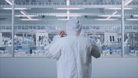 back view of asian male scientist having a headache while standing in modern lab factory with automated robots