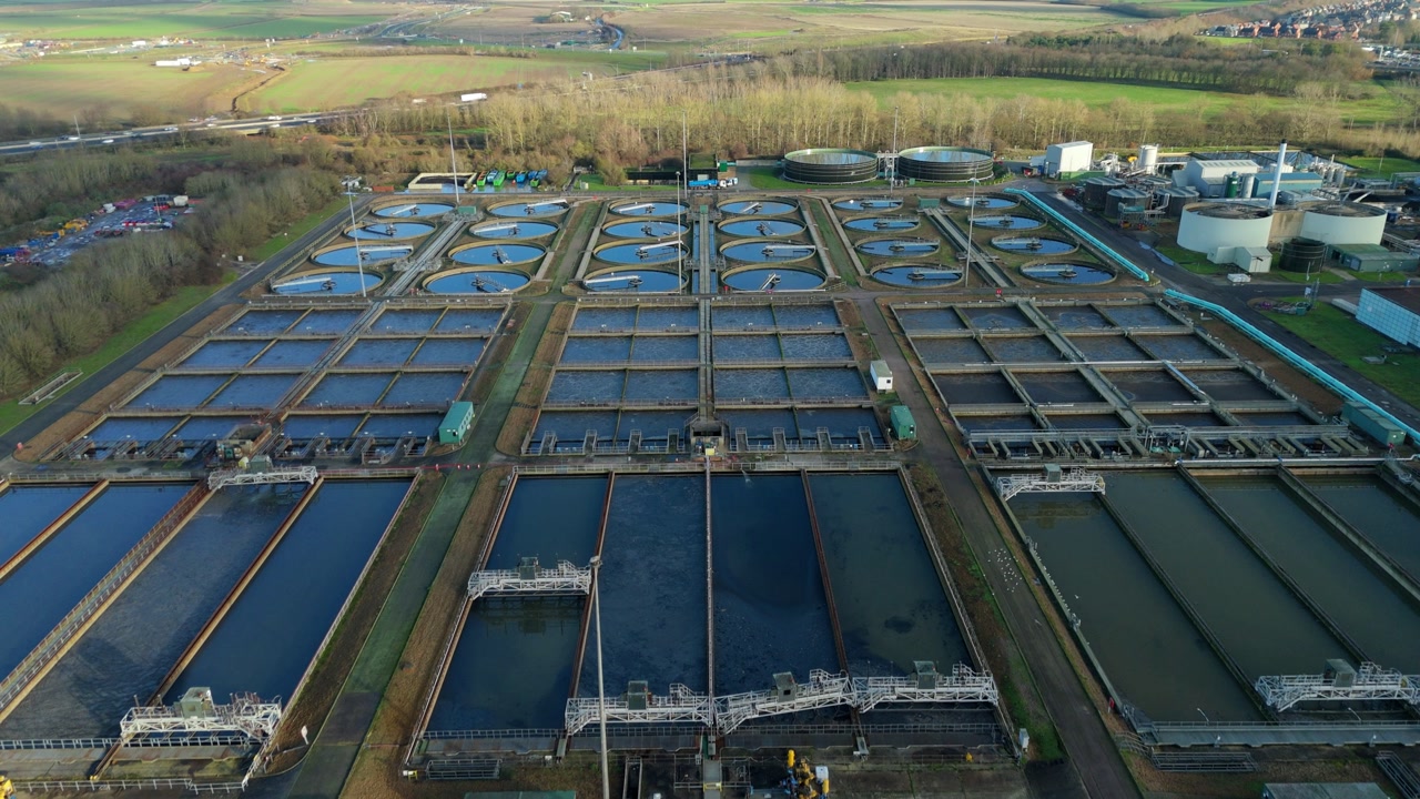 Drone view of large-scale sanitation infrastructure in Milton Keynes, showcasing the symmetrical layout of sedimentation basins and aerobic digestion tanks.