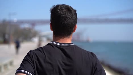 Back-view-of-young-sportsman-running-at-riverside