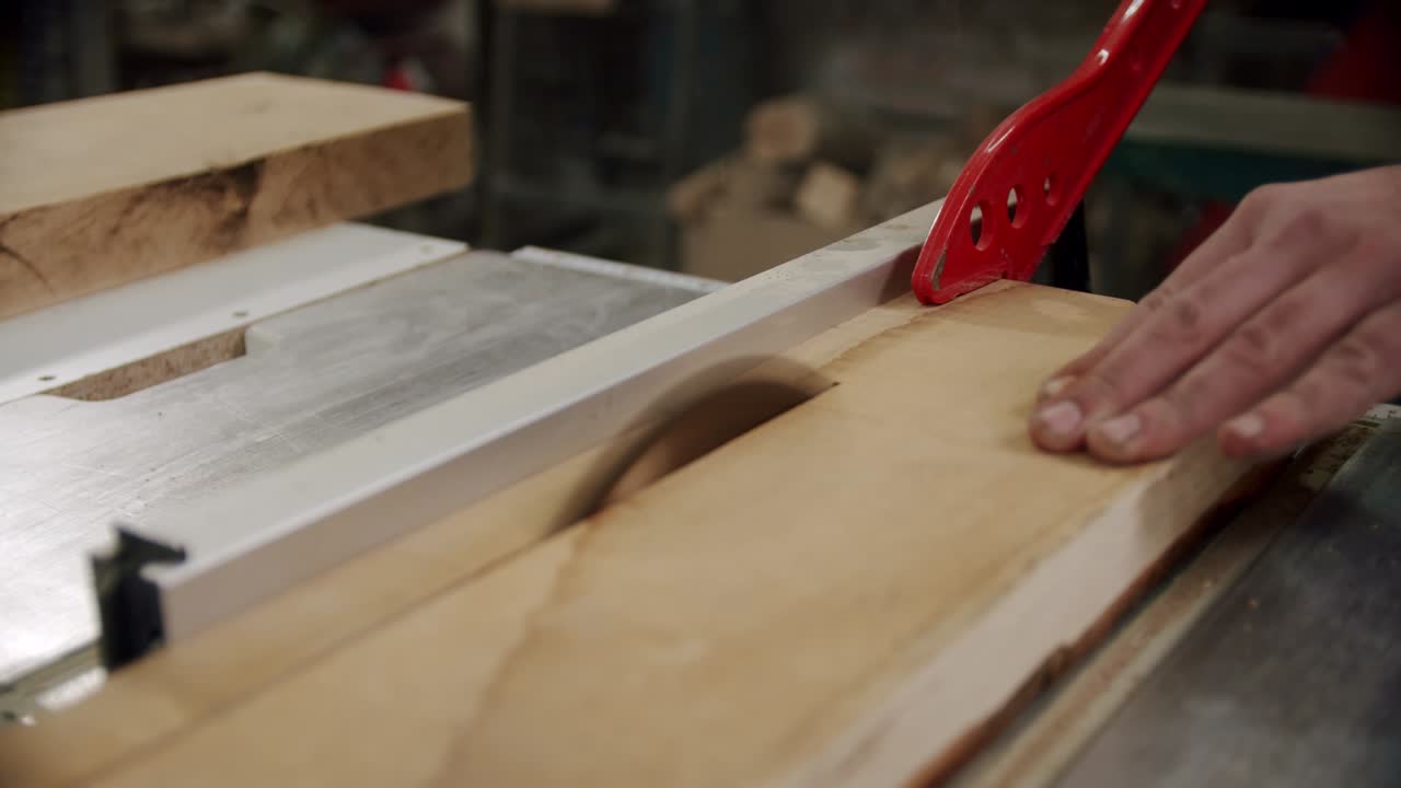 de cerca. el maestro corta una tabla de madera con una sierra circular en el taller de carpintería de un pequeño fabricante de muebles. cámara lenta. v2