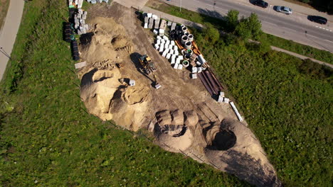 aerial top-down view - excavator working on a construction site - heavy construction equipment - construction yard - storage area