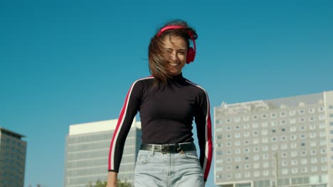 Zoom-in-of-an-Empowered-Happy-Young-Attractive-Latin-Woman-enjoy-dancing-listening-to-music-with-wireless-red-headphones-at-the-city