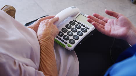 community nurse showing senior woman how to use over sized phone