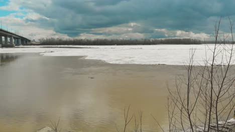 paisaje de amplio río parcialmente derretido por el hielo.