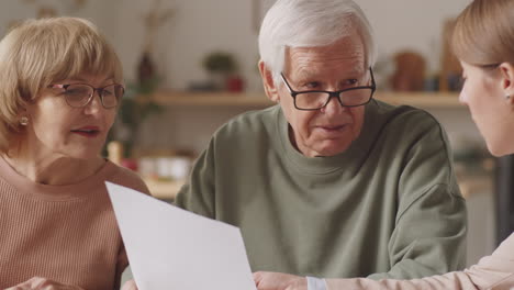 Female-Insurance-Agent-Discussing-Contract-with-Senior-Couple