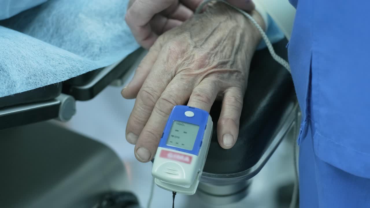 Old patient with pulse oximeter on finger for monitoring during surgery in hospital