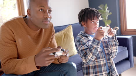 African-american-man-sitting-on-bed-using-tablet-at-home,-slow-motion