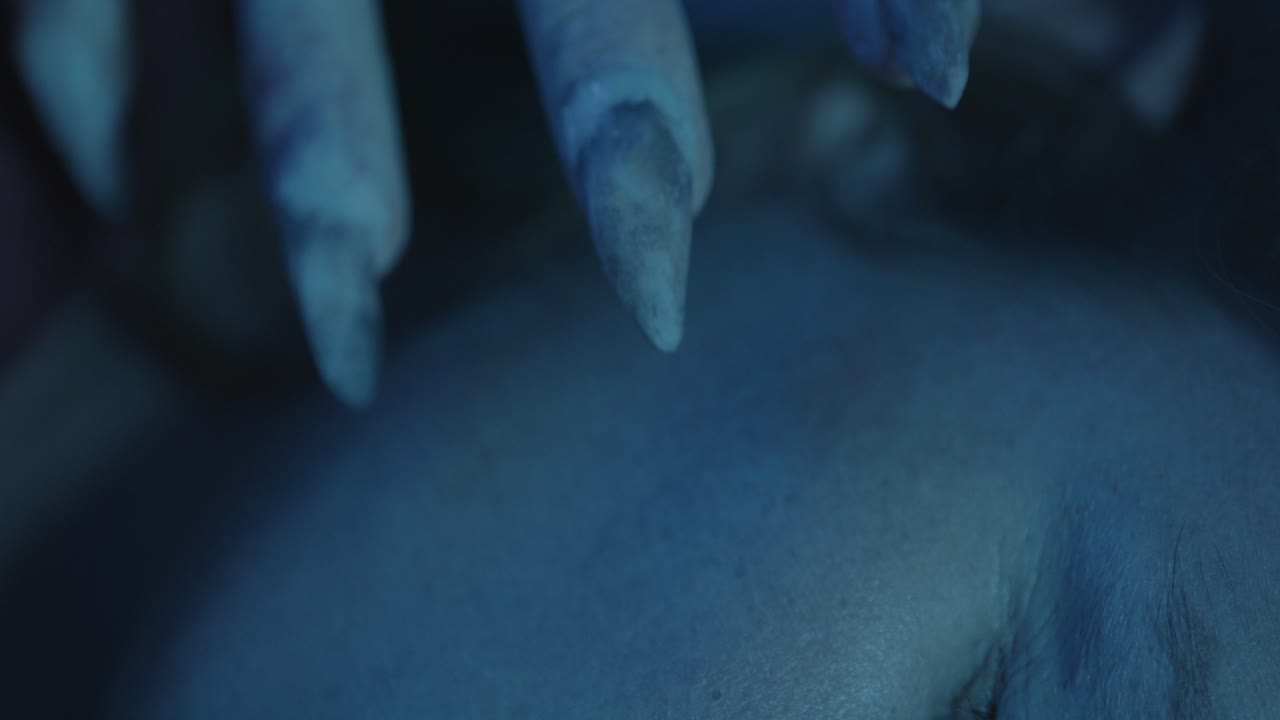 Macro view of a Monster claw touching a sleeping woman's cheek