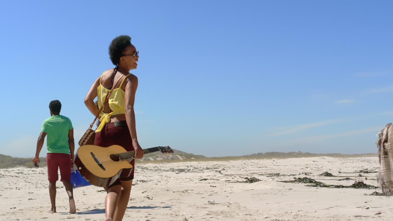 해변 4k에서 피크닉 물건을 운반하는 그룹 친구