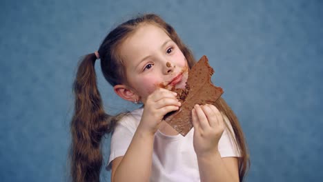 young girl eating chocolate bar. happy cutegirl isolated over background eating chocolate