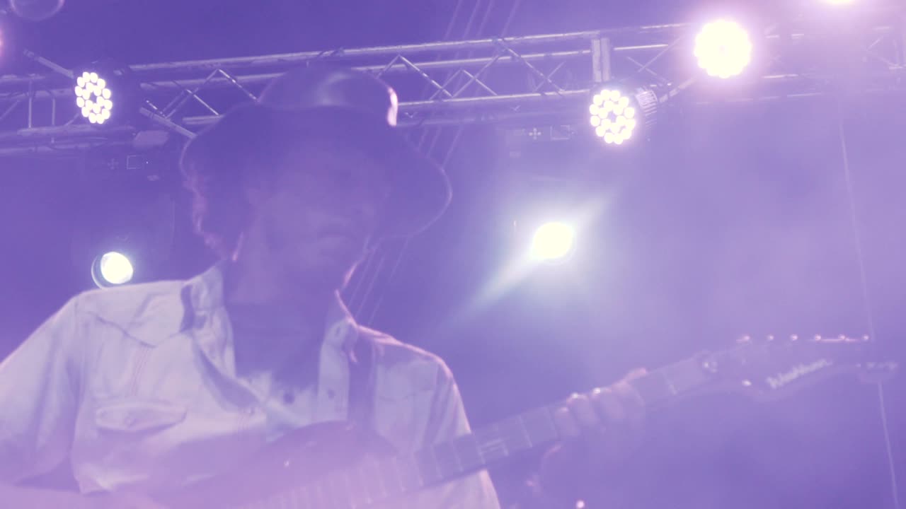cerca en cámara lenta de un guitarrista interpretando una canción en un concierto nocturno al aire libre
