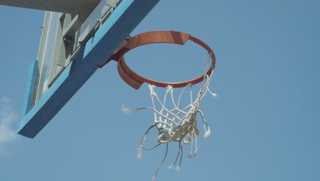 pan to outdoor basketball board with torn net on the hoop