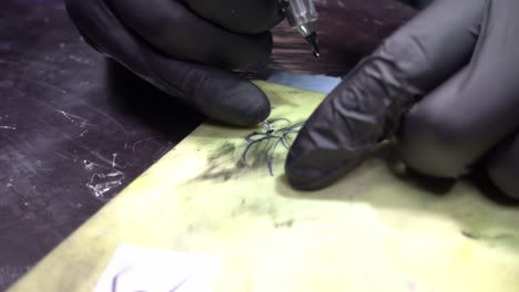 a tattoo artist drawing a black widow spider on syhthetic skin