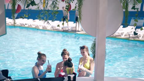 chicas de pie en el agua en la playa hablando y bebiendo cócteles refrescantes