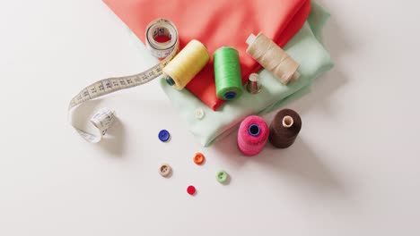 video of folded fabric with tape measure, buttons and cotton reels on white background