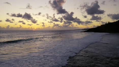 vista aérea de una hermosa puesta de sol en el océano mientras las olas rompen en una playa