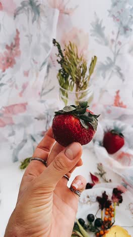 strawberry in hand with floral decor