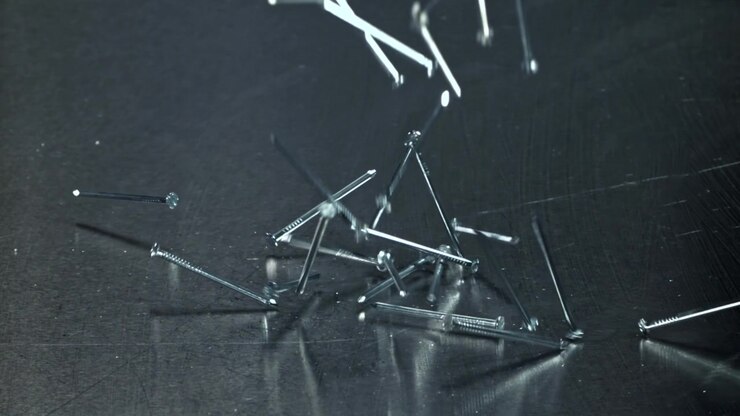 Metal Nails Falling in Slow Motion onto a Dark Reflective Surface