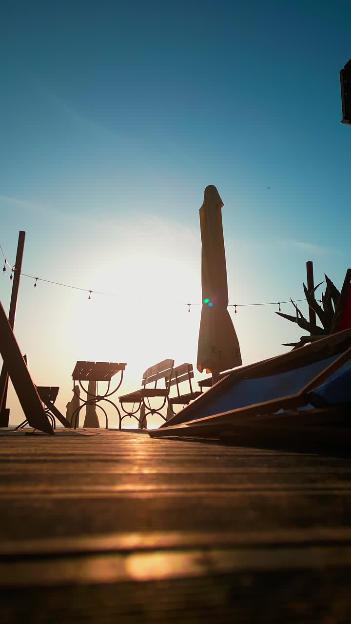 Holiday resort beach parasol backlit in morning sun on wood decking