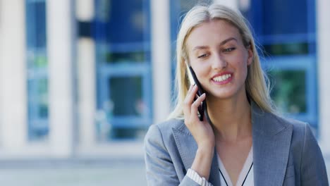cheerful businesswoman talking on phone near building