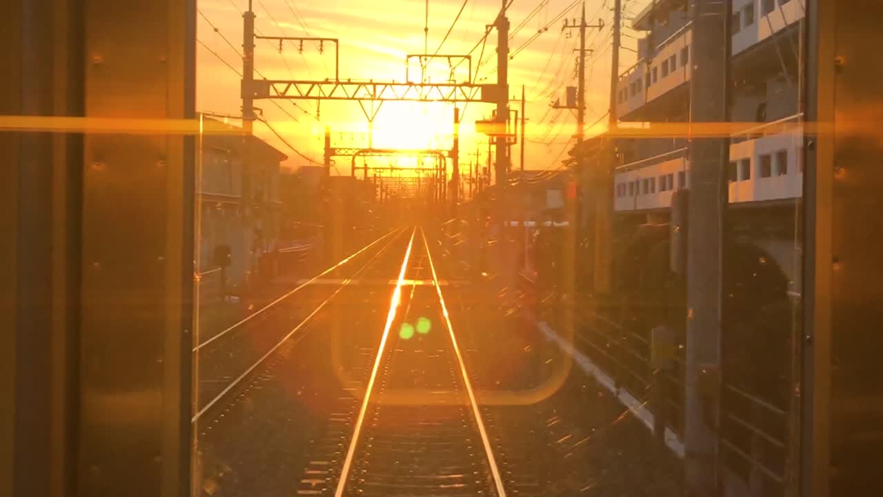 View from back of train through a window of a sunset hitting the tracks in Tokyo, Japan.