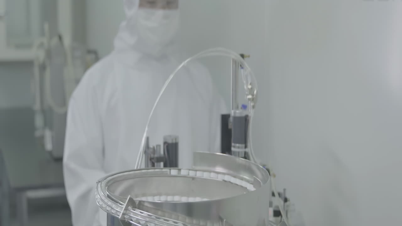 Scientist operate vaccine capping process in automated pharmaceutical production line manufacturing, cap placing on vials of vaccine injections drugs in a sterile factory environment setting.